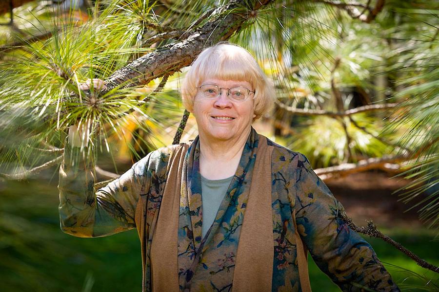 Dr. Carol Miller stands with a longleaf pine last summer at Lovett Pinetum in Strafford, Missouri. During her 40 years of teaching, Miller has taken a special interest in environmental law. (图片来源:Kevin White /密苏里州立大学)